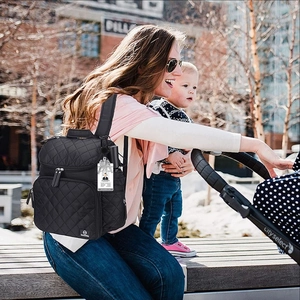 Close-up of quilted black backpack with name tag detail in outdoor parenting usage scenario