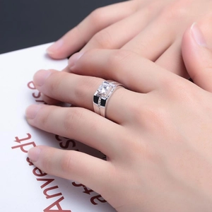Detail of a square-cut zircon ring on a hand showing side channel setting and silver finish