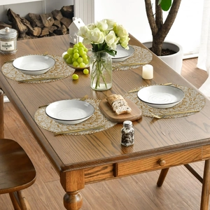 Set of 4 round linen placemats with gold mandala patterns on a wooden table