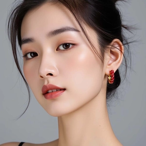 Fashionable red enamel C-shaped hoop earrings with gold spiral details worn by a model