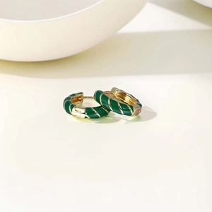 Macro detail of emerald green enamel striped gold hoop earrings with polished finish