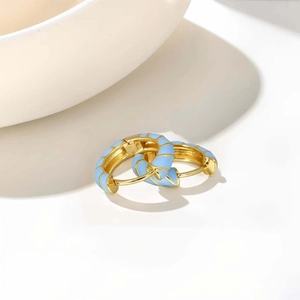 Detail of gold hoop earrings with light blue enamel spiral texture on white background
