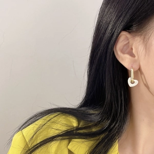 Close-up of heart-shaped white and gold earring worn by model in elegant style
