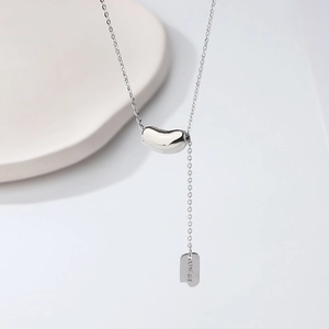 Close-up of 925 silver lucky bean necklace featuring a hanging tag with LUCKY engraving