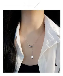 Detailed view of silver lucky bean pendant and engraved LUCKY tag on delicate neck chain