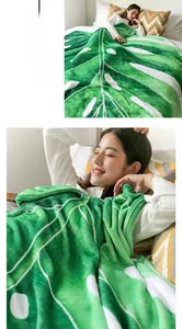 Detail showing soft green monstera leaf shaped flannel blanket in a cozy bedroom scene