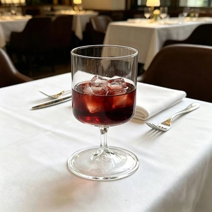 Elegant high borosilicate glass champagne flute with red wine and ice on white tablecloth