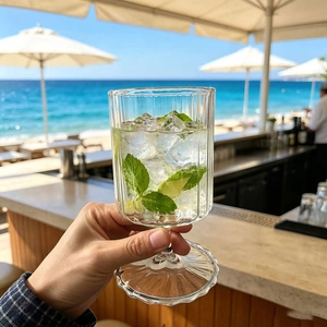 Close-up of ribbed borosilicate glass cocktail cup with mint and lime on beach