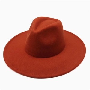 Detail view of a rust red wide brim wool fedora with structured crown and flat edge