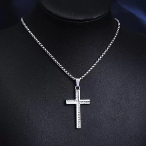 Close-up of silver cross pendant with sparkling rhinestones on a black neck model