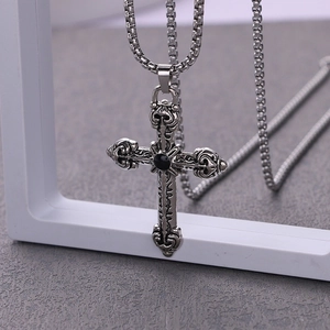 Close-up of gothic cross pendant with black onyx stone and intricate floral engravings