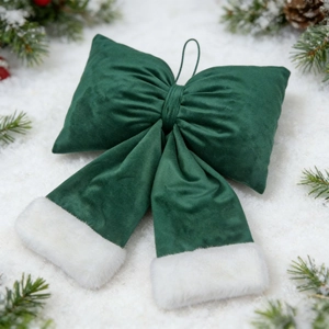Macro shot of dark green velvet Christmas bow with white faux fur trim on snow