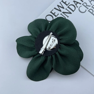 Detailed back view of the dark green fabric flower pin with metal clip and safety pin