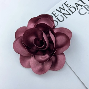 Macro shot of handcrafted burgundy satin floral brooch with layered petals and metal pin