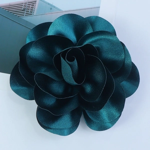 Macro detail of 14cm emerald green satin fabric flower with layered petals and silk texture