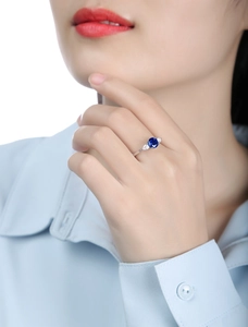 Detailed close-up of a blue sapphire silver ring on model's hand with side teardrop stones