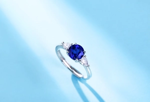 Macro shot of silver ring featuring a blue sapphire centerpiece and side diamonds