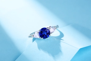 Macro shot of silver ring with round blue sapphire and two pear-shaped side stones