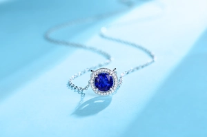 Macro shot of silver pendant featuring a round sapphire center stone with halo diamonds