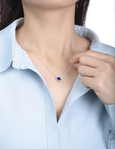 Close-up of S925 silver necklace with a round blue sapphire pendant worn on a model