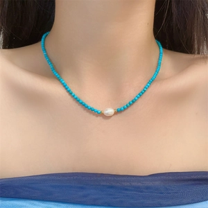 Detail of turquoise beaded necklace featuring a white freshwater pearl with gold spacers