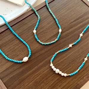 Detail of turquoise bead necklaces with freshwater pearls and gold spacers on wood