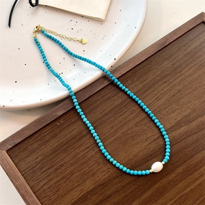 Detailed close-up of natural turquoise beads and a freshwater pearl on a gold clasp