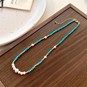 Detail of turquoise beads with freshwater pearls on a dark wood jewelry tray