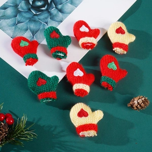 Close-up of mini knitted Christmas gloves with heart patterns and fuzzy white cuffs for DIY crafts