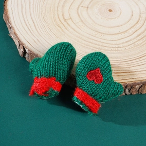 Close-up of green knitted Christmas mini gloves with red fur trim and heart embroidery