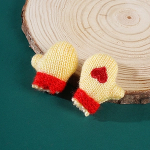 Close-up of mini yellow knitted gloves with red heart embroidery for Christmas decor