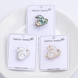 Detailed view of three cute rabbit brooches with shell inlay on a white porcelain plate