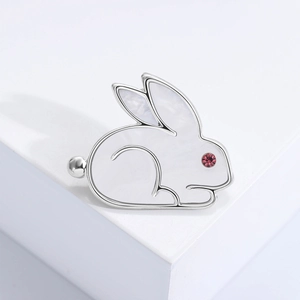 Close-up of a silver rabbit brooch with white mother-of-pearl shell and purple gem eyes
