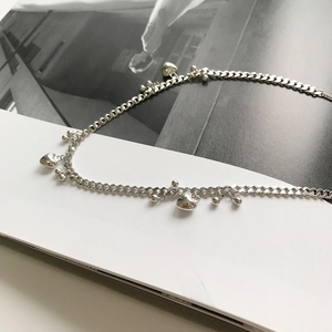 Detail of S925 silver necklace featuring beaded chain and polished heart charms on a magazine