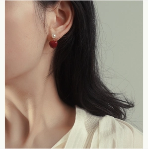 Nahaufnahme von 925er Silberohrring mit eleganter weißer Perle und glänzend rotem Herzanhänger