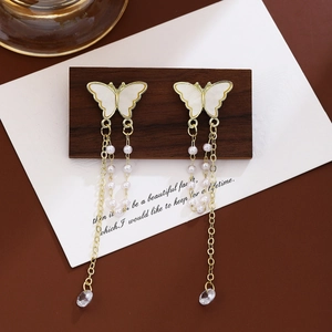 Close-up of butterfly earrings with pearl tassels and teardrop crystal on wood