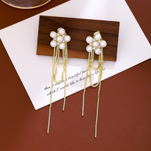 Close-up of elegant gold tassel earrings with six-petal pearl flowers and diamond accents