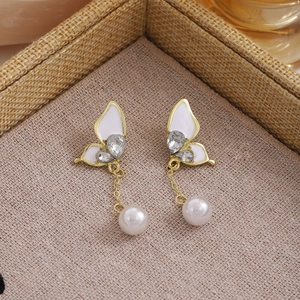 Detail of butterfly drop earring with white enamel wings and hanging pearl accent