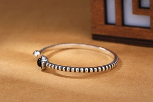 Macro view of vintage silver twist bangle featuring a round black onyx stone setting