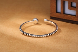 Close-up of vintage silver beaded open bangle with black agate accent and retro texture