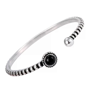 Macro detail of retro silver cuff bracelet featuring black onyx stone and textured patterns