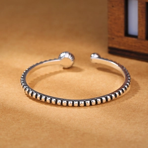 Vintage silver beaded open bangle with round texture on orange aesthetic background