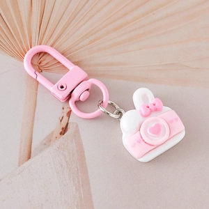Simpatico portachiavi a fotocamera rosa e bianco con dettaglio a cuore e fiocco