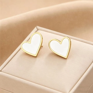 Elegant 18K gold plated heart stud earrings with white enamel finish on a beige jewelry box