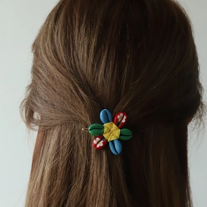 Ethnic flower hair clip with colorful shell-like petals and floral print on brown hair