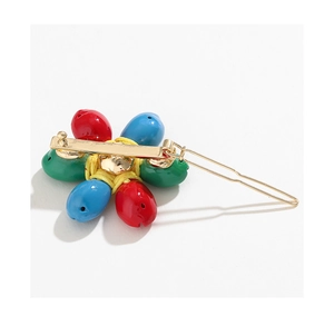 Detail of flower hair clip with red blue green teardrop beads on gold metal base