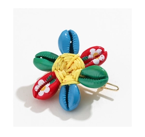 Macro shot of tropical flower hair clip made of colorful painted shells and gold metal base