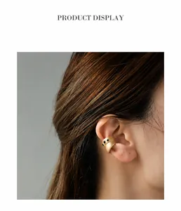 Detail of matte gold ear cuff with black crystal accents shown on a model's ear