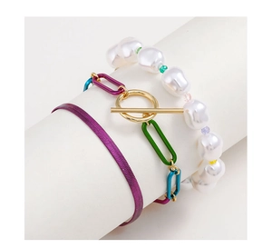 Dettaglio di bracciali a strati con perle, maglie colorate e una catena a serpente