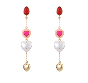Detail view of long heart-shaped drop earrings with red gems and pearl texture pendants